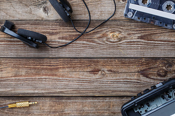 Image showing Cassette tape, cassette player and headphones over wooden table. top view.