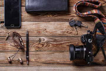 Image showing Travel concept - headphones, camera,  sketchbook, purse, pencil and keys on wooden background.