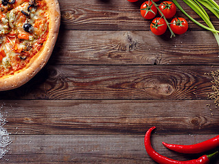 Image showing Italian pizza with tomatoes on a wooden table, top view.