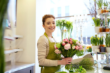 Image showing smiling florist woman making bunch at flower shop