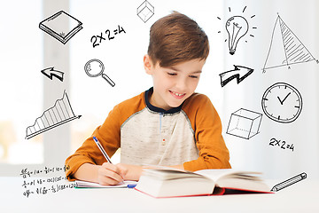 Image showing smiling student boy writing to notebook at home