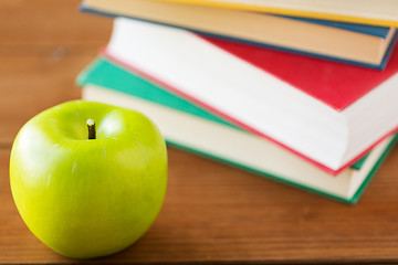 Image showing close up of books and green apple on wooden table