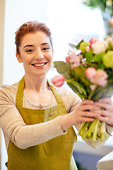 Image showing smiling florist woman making bunch at flower shop