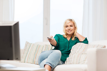 Image showing smiling woman with remote watching tv at home