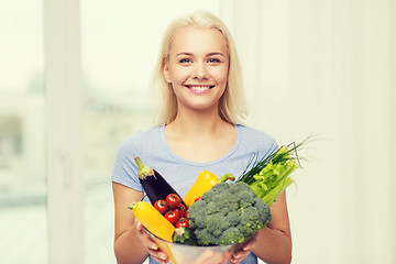 Image showing smiling young woman with vegetables at home