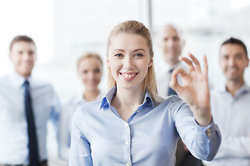 Image showing smiling businesswoman showing ok sign in office