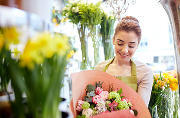 Image showing smiling florist woman with bunch at flower shop