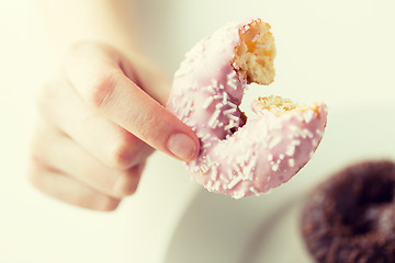 Image showing close up of hand holding bitten glazed donut