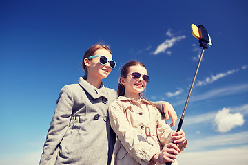 Image showing happy girls with smartphone selfie stick