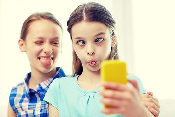 Image showing happy girls with smartphone taking selfie at home