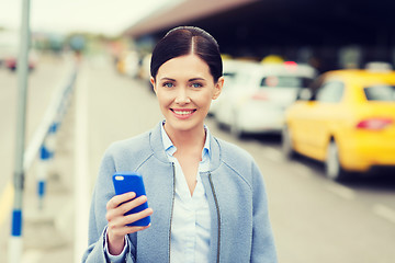 Image showing smiling woman with smartphone over taxi in city