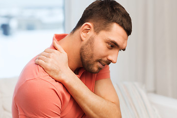 Image showing unhappy man suffering from neck pain at home