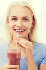 Image showing smiling woman drinking juice or shake at home