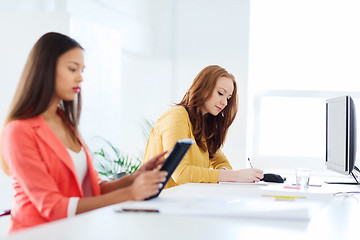 Image showing creative female office worker writing to notebook