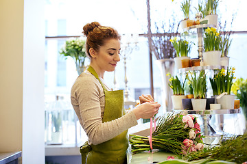 Image showing smiling florist woman making bunch at flower shop