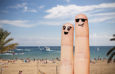 Image showing close up of two fingers with smiley faces on beach