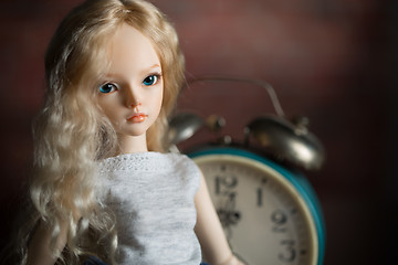 Image showing doll on the background of the old clock.