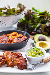 Image showing Grilled chicken legs and wings with guacamole