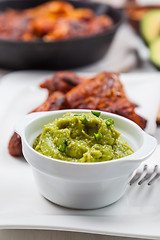 Image showing Grilled chicken legs and wings with guacamole