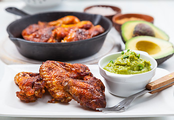 Image showing Grilled chicken legs and wings with guacamole