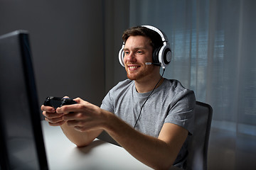 Image showing man in headset playing computer video game at home