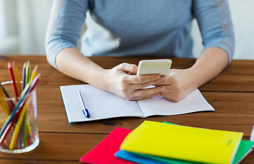 Image showing close up of student with smartphone and notebook