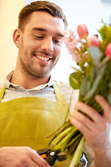 Image showing smiling florist man making bunch at flower shop