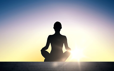 Image showing woman meditating in yoga lotus pose over sun light