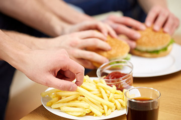 Image showing close up of male hands with fast food on table