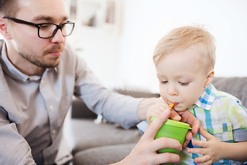 Image showing father and son drinking from cup at home