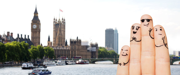 Image showing close up of fingers with smiley faces over london