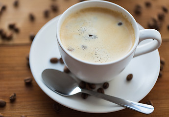 Image showing close up coffee cup and grains on wooden table