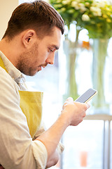 Image showing florist man texting on smartphone at flower shop