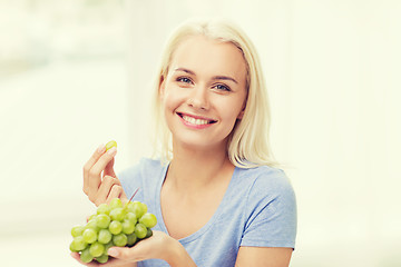 Image showing happy woman eating grapes at home