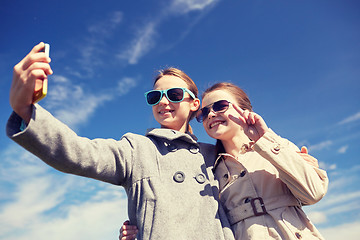 Image showing happy girls with smartphone taking selfie outdoors
