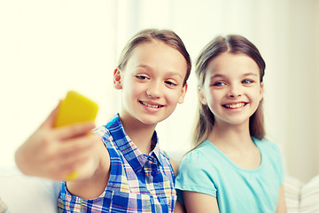 Image showing happy girls with smartphone taking selfie at home