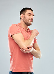 Image showing unhappy man suffering from pain in hand