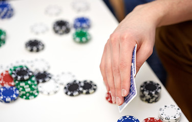 Image showing close up of male hand with playing cards and chips