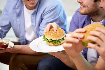 Image showing close up of friends eating hamburgers at home