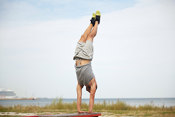 Image showing young man exercising on bench outdoors