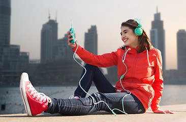 Image showing happy young woman with smartphone and headphones