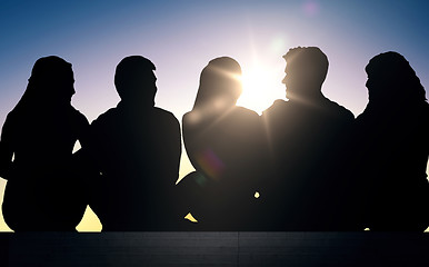 Image showing silhouettes of friends sitting on stairs over sun