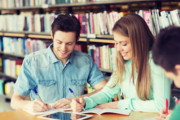 Image showing happy students writing to notebooks in library