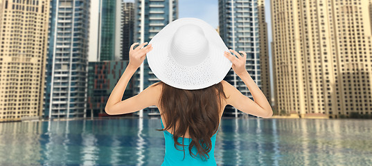 Image showing woman in sun hat from back over dubai city pool