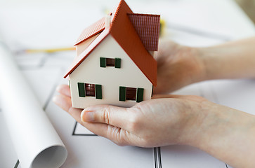 Image showing close up of hands with house model above blueprint