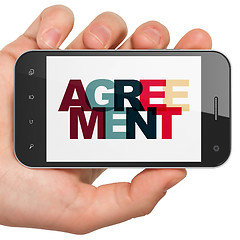 Image showing Finance concept: Hand Holding Smartphone with Agreement on  display