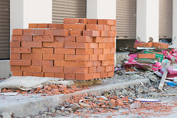 Image showing New bricks are stacked on a pallet stand at the trade pavilions around construction debris