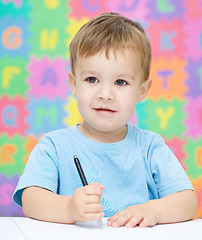 Image showing Little boy is writing on his copybook