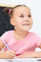 Image showing Little girl is writing using a pen