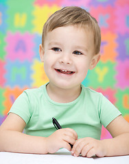 Image showing Little boy is writing on his copybook